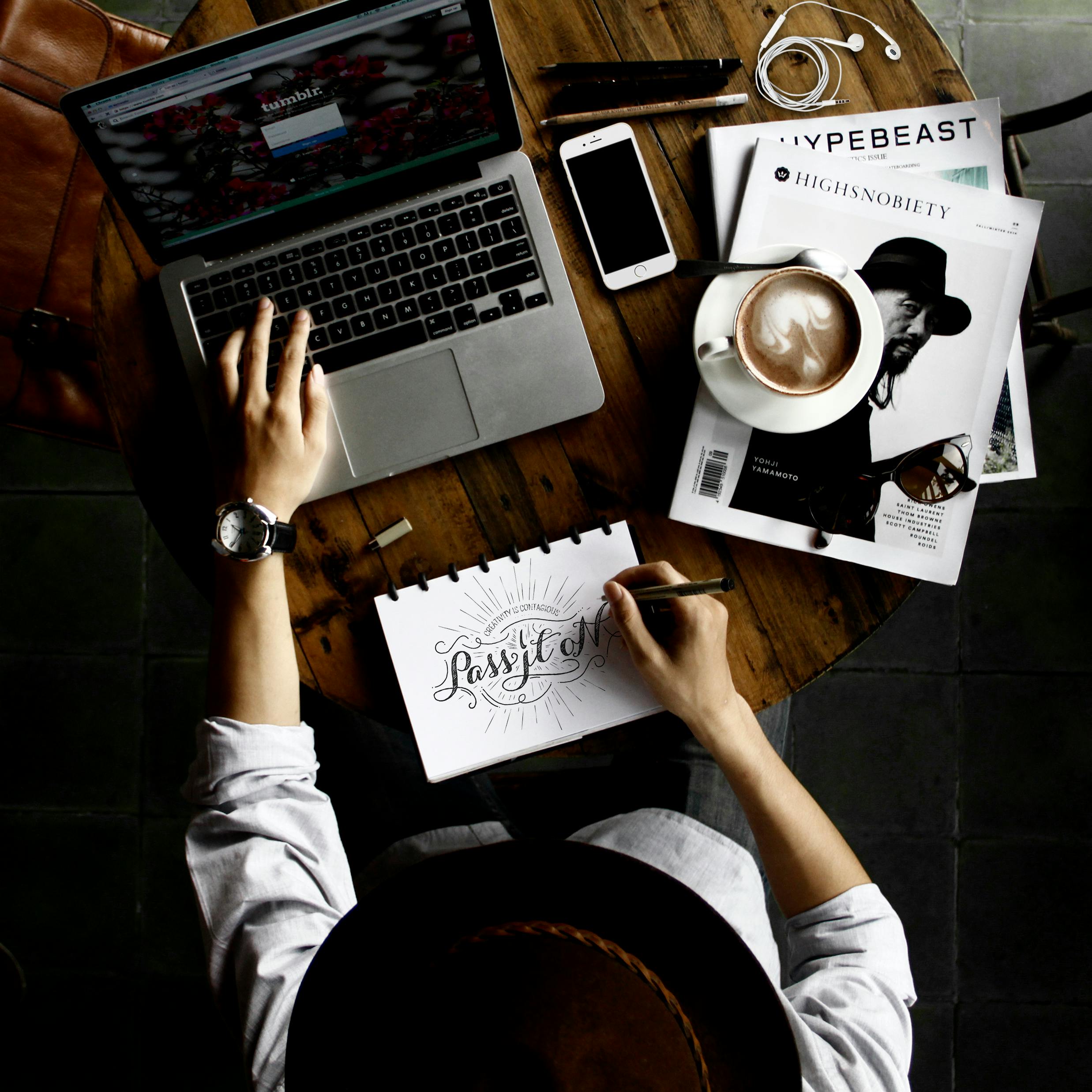 Person sitting facing laptop computer with sketch pad